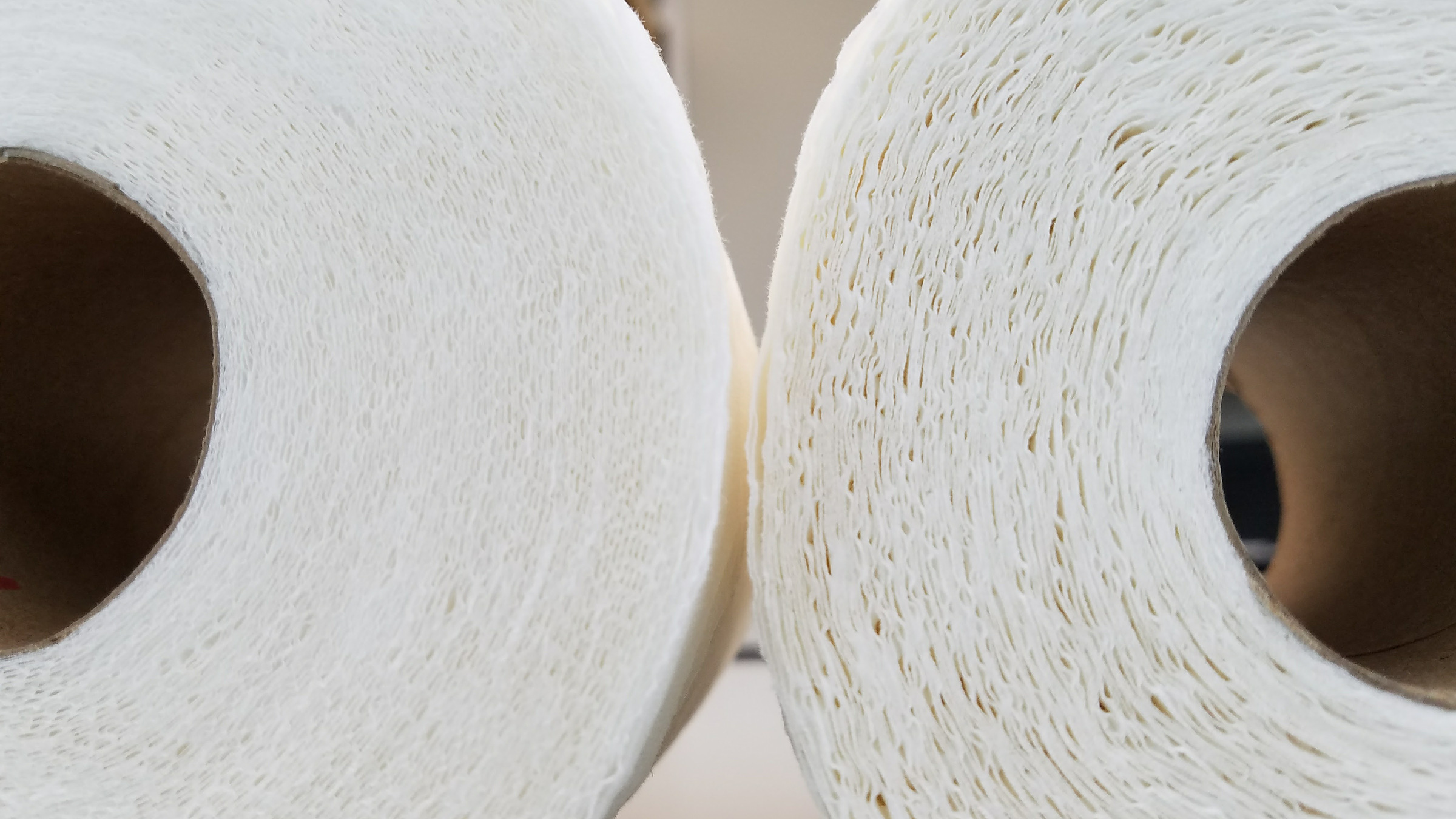 Close-up of two tissue rolls side by side showing different sheet density and structure
